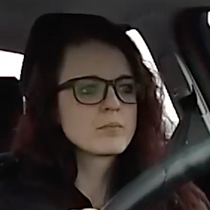 headshot of woman with glasses in driver seat of vehicle